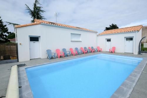 une piscine avec des chaises rouges à côté d'un bâtiment dans l'établissement Au Logis des Mûriers, à Vairé