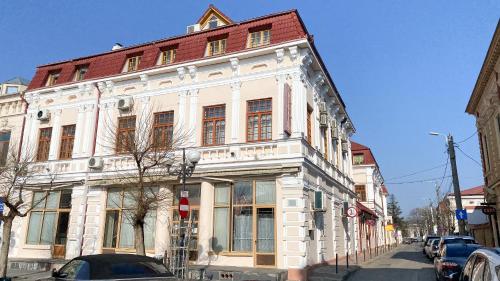 a white building with a red roof on a street at Hotel Regal in Brăila