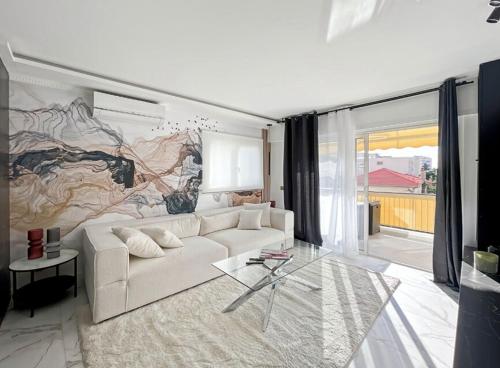 un salon avec un canapé blanc et une grande fresque murale. dans l'établissement Appartement Moderne à Cannes, à Cannes