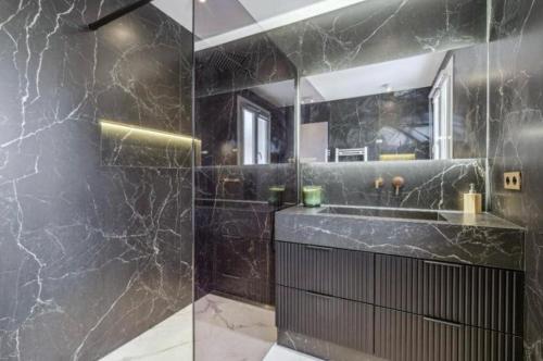une salle de bain noire avec un lavabo et un miroir dans l'établissement Appartement Moderne à Cannes, à Cannes