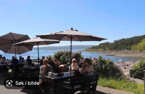 a group of people sitting at a table with umbrellas at Extravagant villa central & by the sea in Oslo