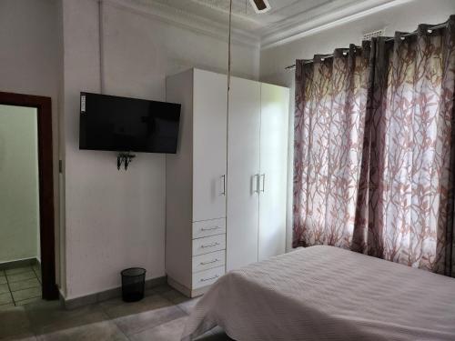 a bedroom with a bed and a tv on the wall at Idube Power Hub Guest House in Benoni