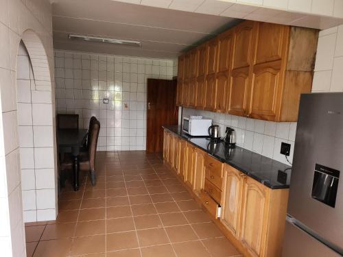 a kitchen with wooden cabinets and a black counter top at Idube Power Hub Guest House in Benoni