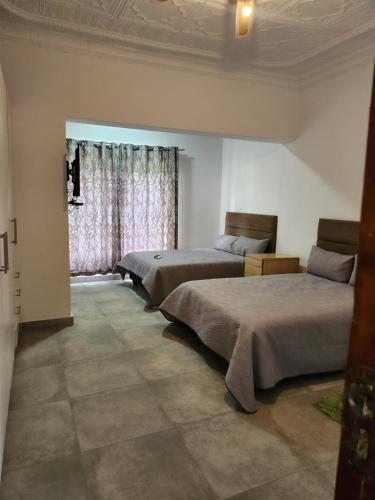 a bedroom with three beds and a window at Idube Power Hub Guest House in Benoni