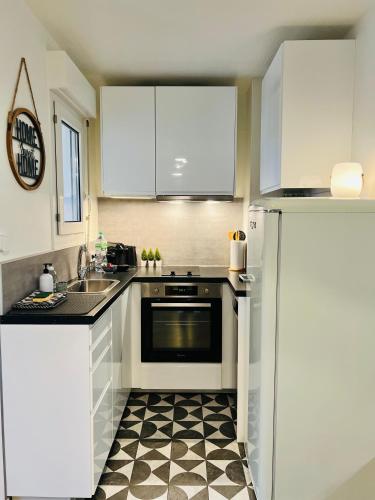 - une cuisine avec des placards blancs et un sol noir et blanc dans l'établissement T2 Beaux Arts parking privé gratuit, à Montpellier