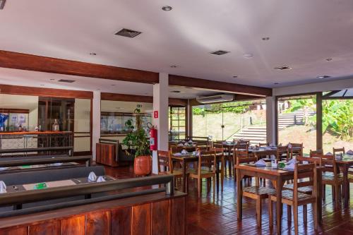 a restaurant with wooden tables and chairs and windows at Hotel Colonial Iguaçu in Foz do Iguaçu