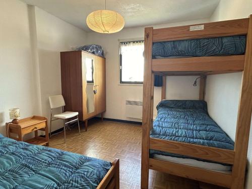 - une chambre avec des lits superposés et une couette bleue dans l'établissement Appartement cosy 3 pièces avec parking et animaux admis - FR-1-224B-134, à Noirmoutier-en-l'lle