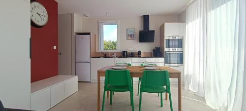 une cuisine avec une table en bois et des chaises vertes dans l'établissement Maison 2 chambres - proche de tout - Jacuzzi privatif, à Les Sables-dʼOlonne