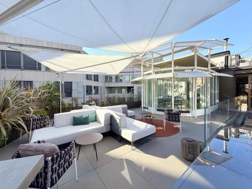 a rooftop patio with a white couch and tables at The Street Milano Duomo | a Design Boutique Hotel in Milan