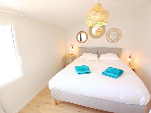 - une chambre dotée d'un lit blanc avec des oreillers bleus dans l'établissement Maison 2 chambres - proche de tout - Jacuzzi privatif, à Les Sables-dʼOlonne