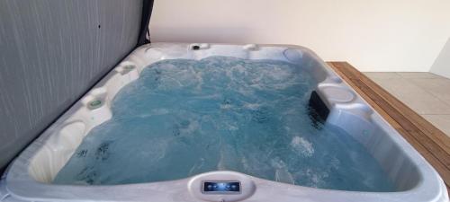 une baignoire remplie d'eau bleue dans une salle de bain dans l'établissement Maison 2 chambres - proche de tout - Jacuzzi privatif, à Les Sables-dʼOlonne