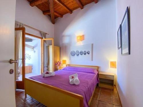 a bedroom with a purple bed with two towels on it at Villa Lorenza in Baja Sardinia
