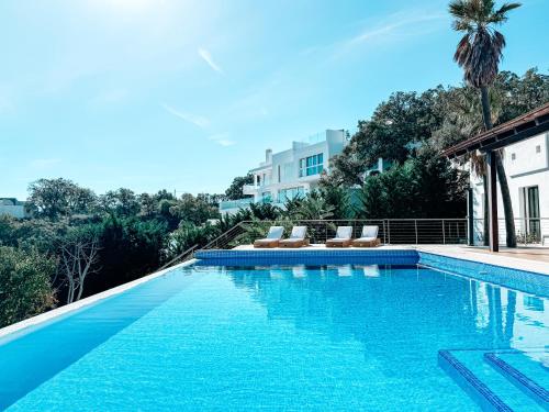 a swimming pool with chairs and a building at Luxury Boutique B&B - Villa Prana Marbella in Ojén