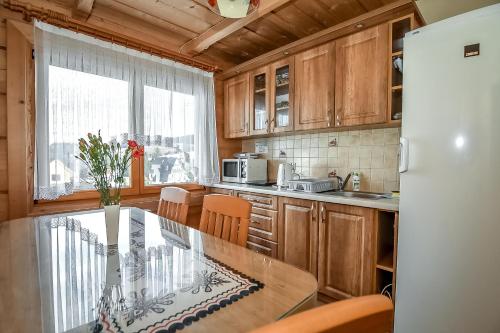 a kitchen with wooden cabinets and a glass table at U Justynki in Małe Ciche