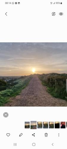 a picture of a dirt road with the sun in the distance at Bleij-en-meer, 2 accommodaties, waarvan 1 een 4p huisje is en 1 een Tiny-Wellness huisje voor 2p met sauna en heerlijke hottub, ook samen te huur voor een gezellig combinatie in Zoutelande