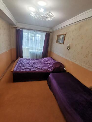 a bedroom with two beds and a window with purple sheets at Просторі апартаменти на ВДНГ in Kyiv