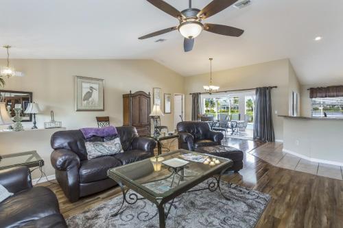 a living room with leather furniture and a ceiling fan at Herons' View Villa in Biggar