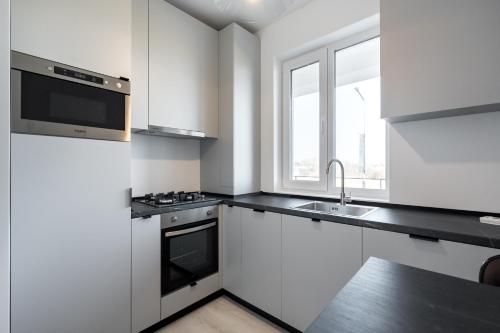 a white kitchen with a sink and a microwave at AeroPrime - LOFT in Tunari