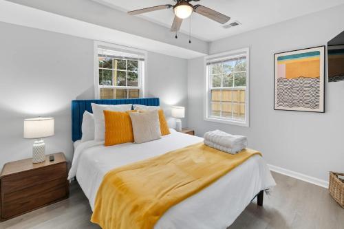 a bedroom with a large bed and two windows at Palmetto Porch - Family Home Near Park Circle in Charleston