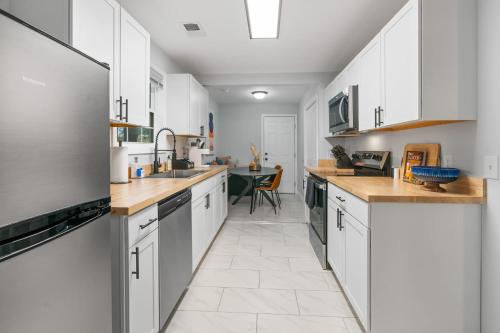 a large kitchen with white cabinets and a table at Palmetto Porch - Family Home Near Park Circle in Charleston