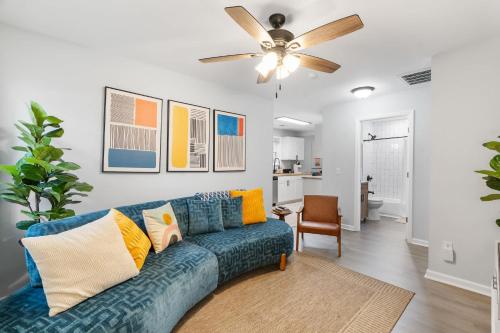 a living room with a blue couch and a ceiling fan at Palmetto Porch - Family Home Near Park Circle in Charleston