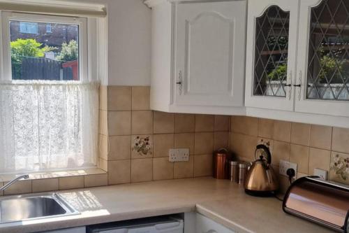 a kitchen with white cabinets and a sink and a window at Doncaster-House-Sleeps8-Parking-Garden in Doncaster