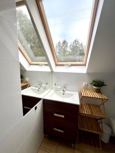 a bathroom with two sinks and a skylight at Dom pod świerkiem in Małe Swornigacie