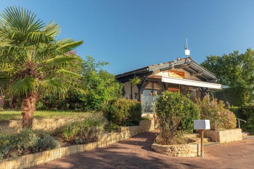 a building with a palm tree in front of it at Camping Le Mas de Sireuil in Sireuil