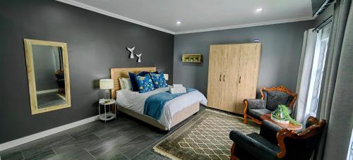 a bedroom with a bed and a chair and a mirror at Hartklop Luxury Self Catering Guesthouse in Linkside