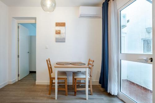 a dining room with a table and chairs and a window at Casa con encanto - Wifi, aire acondicionado in Puerto Real