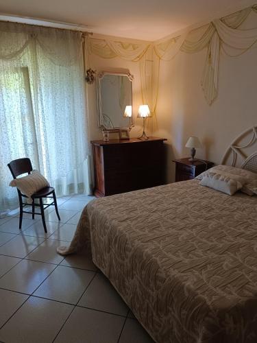 a bedroom with a bed and a mirror and a chair at Villa Adriana in Capoliveri