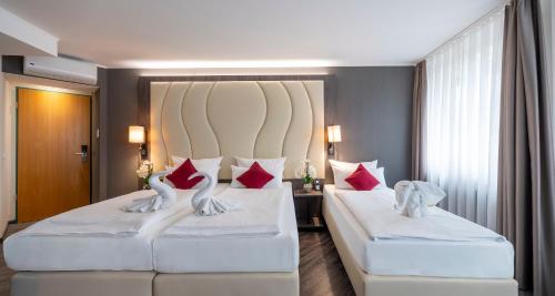 two beds in a hotel room with red pillows at PLAZA INN Blankenburg Ditzingen, Sure Hotel Collection in Ditzingen