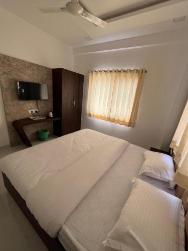 a bedroom with a large white bed and a window at Laxminarayan Executive in Tuljapur