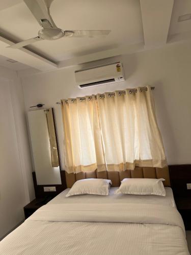 a bedroom with a bed with two pillows and a window at Laxminarayan Executive in Tuljapur