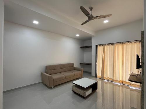 a living room with a couch and a ceiling fan at Laxminarayan Executive in Tuljapur