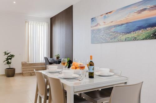 a white dining room with a white table and chairs at Fl 1 Thelodge - Charming Retreat By Homely in Mellieħa