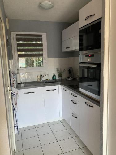 une cuisine blanche avec des armoires blanches et une fenêtre dans l'établissement les maisons bleues, à Capbreton