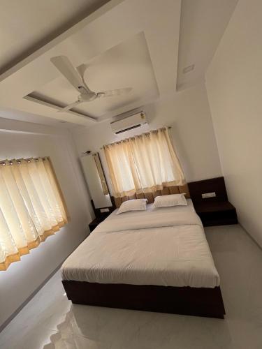 a bedroom with a bed and two windows at Laxminarayan Executive in Tuljapur