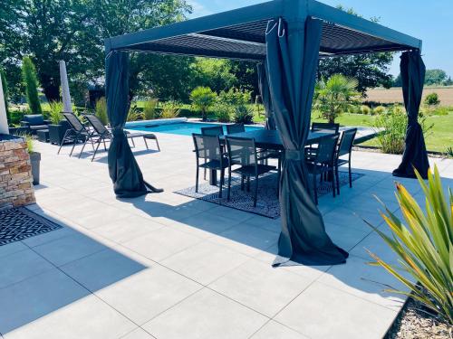 une table et des chaises sous un auvent bleu à côté d'une piscine dans l'établissement Villa 10 min du circuit des 24h du Mans, à Saint-Gervais en-Belin