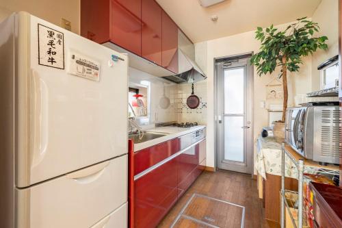 a kitchen with red cabinets and a white refrigerator at GP House in Tokyo
