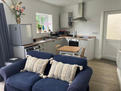 a living room with a blue couch and a kitchen at Pet-friendly boutique beach retreat in Uphill