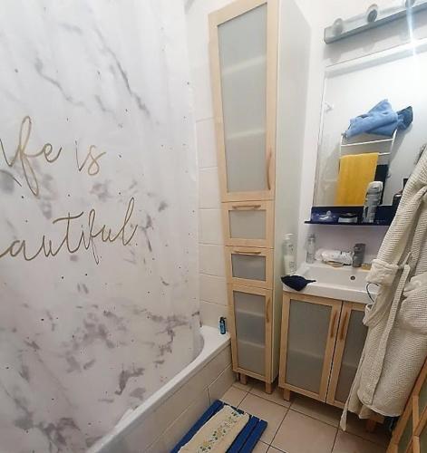 une salle de bain avec une baignoire, un lavabo et un miroir dans l'établissement agreable appartement situe en front de mer, à Soulac-sur-Mer