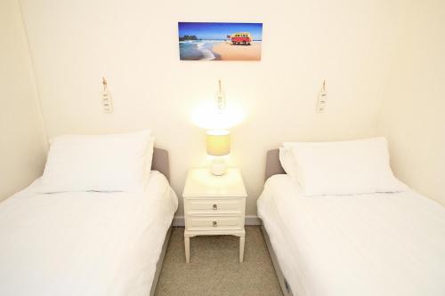 two twin beds in a room with a lamp on a night stand at Harbour Station View in Porthmadog