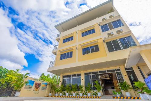 a yellow building with palm trees in front of it at Anahaw Seaside Inn in Bantayan Island