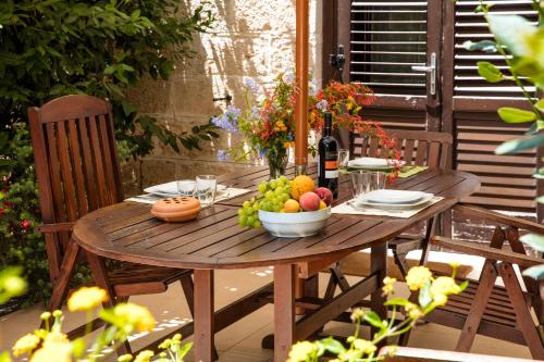 uma mesa de madeira com uma taça de fruta e uma garrafa de vinho em Il Borgo Del Principino em Favignana