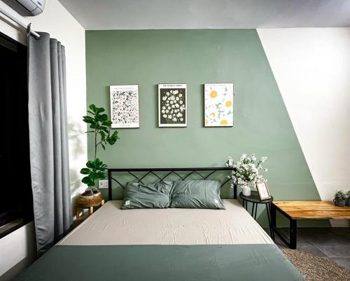 a bedroom with a bed and a green wall at Kayla Homestay - Villa Garden House in Ba Vì
