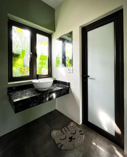 a bathroom with a sink and a window and a door at Kayla Homestay - Villa Garden House in Ba Vì