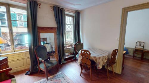 une salle à manger avec une table, des chaises et des fenêtres dans l'établissement Les appartements hyper centre Barr, à Barr