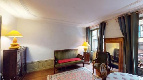 a living room with a chair and a desk and a room with a bed at Les appartements hyper centre Barr in Barr