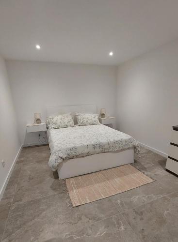 a white bedroom with a bed and two night stands at Estúdio Laura in Câmara de Lobos